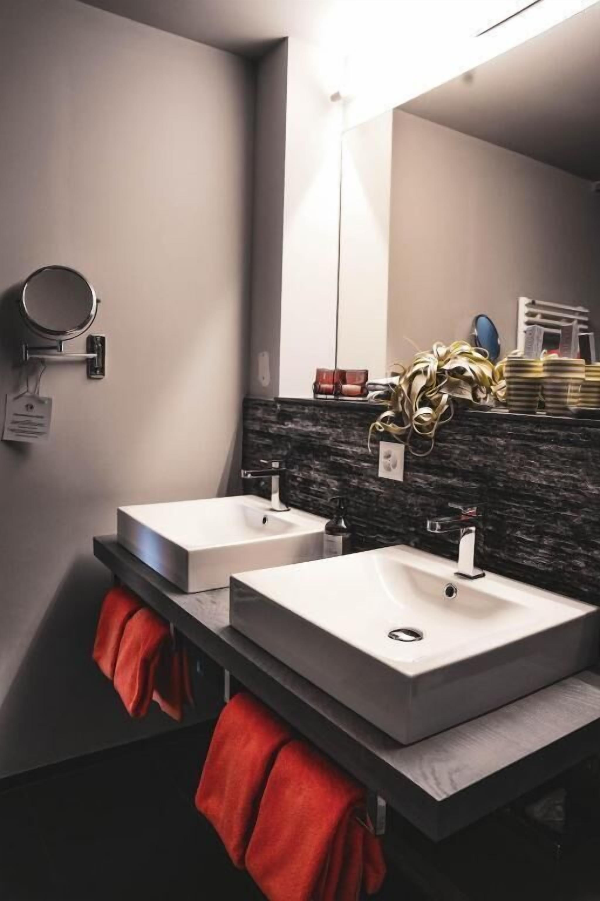 A modern bathroom with two sinks, a mirror, and a towel rack.