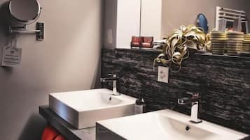 A modern bathroom with two sinks, a mirror, and a towel rack.