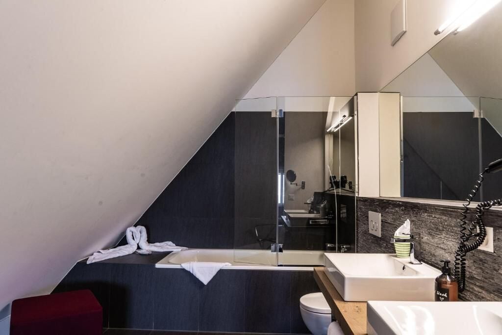 Un baño moderno con cabina de ducha de vidrio, un lavabo blanco y un espejo grande.