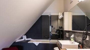 Un baño moderno con cabina de ducha de vidrio, un lavabo blanco y un espejo grande.