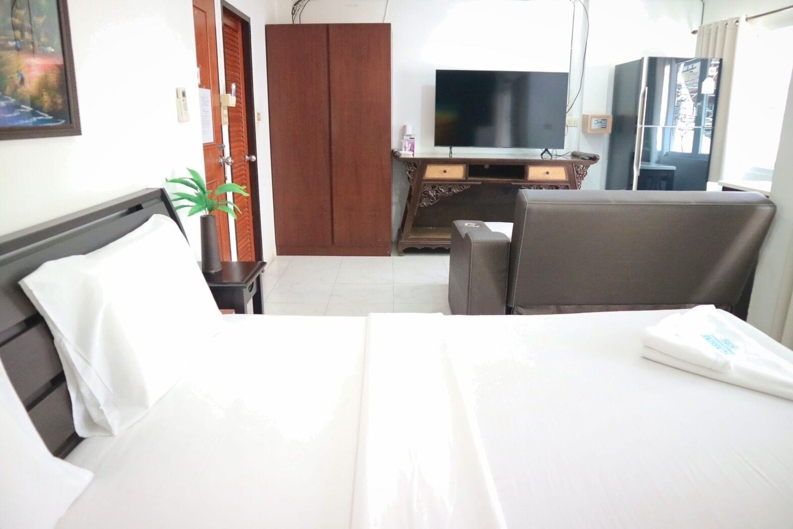 A hotel room with a bed, a desk, a chair, a TV, and a wardrobe.