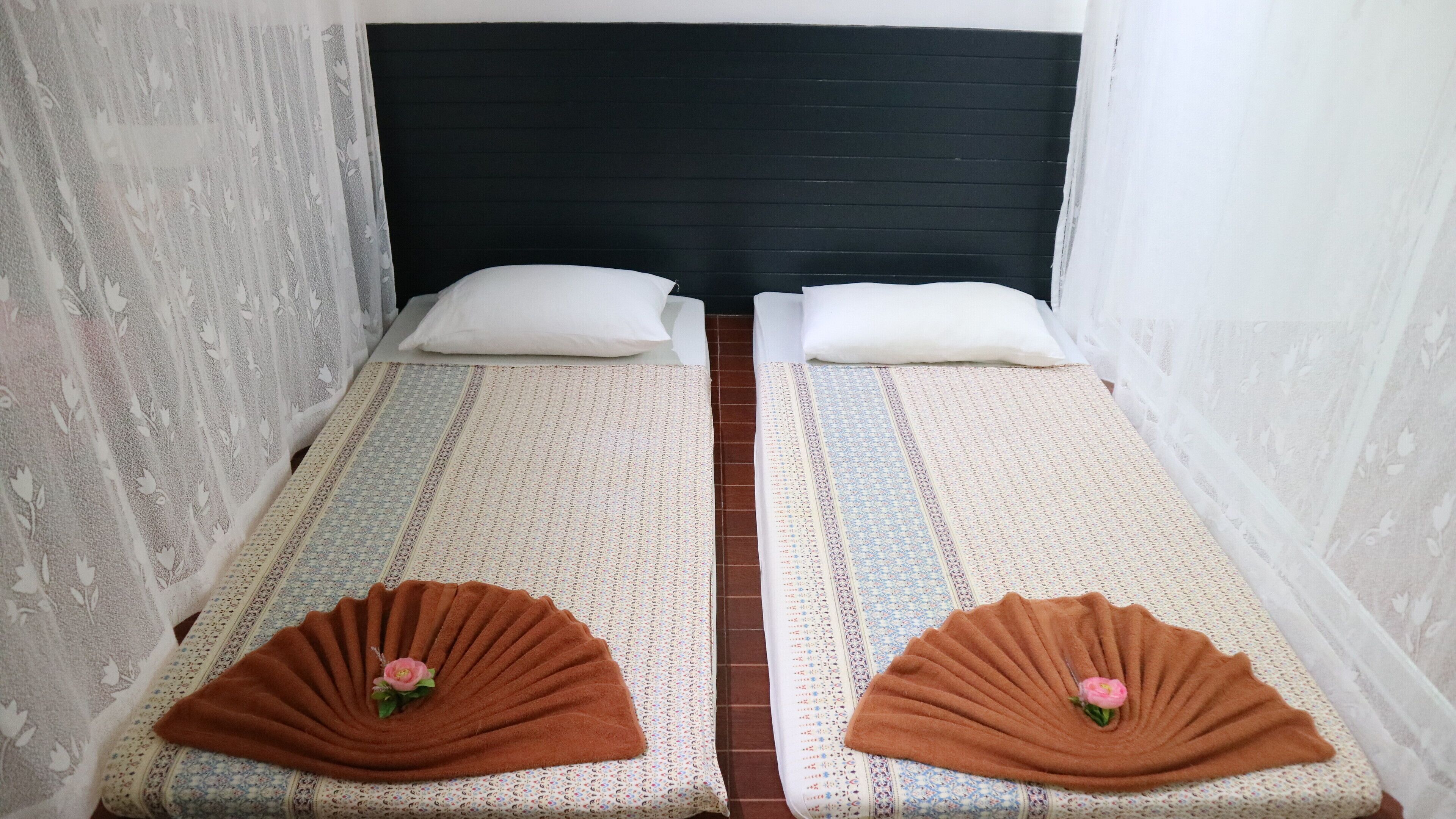 A twin room with two single beds, each with a patterned bedspread and a brown decorative item on the foot of the bed.