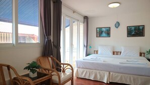 Une chambre d’hôtel avec un lit, une chaise, une table ornée d’une plante et deux tableaux accrochés au mur.