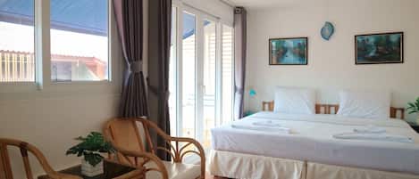 Habitación de hotel con una cama, una silla, una mesa con una planta y dos cuadros en la pared.