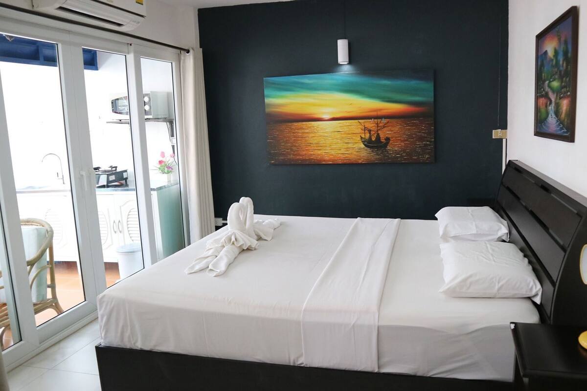 Ein Hotelzimmer mit einem Bett, einem Sonnenuntergangsbild, einem Fenster und einem Sessel.