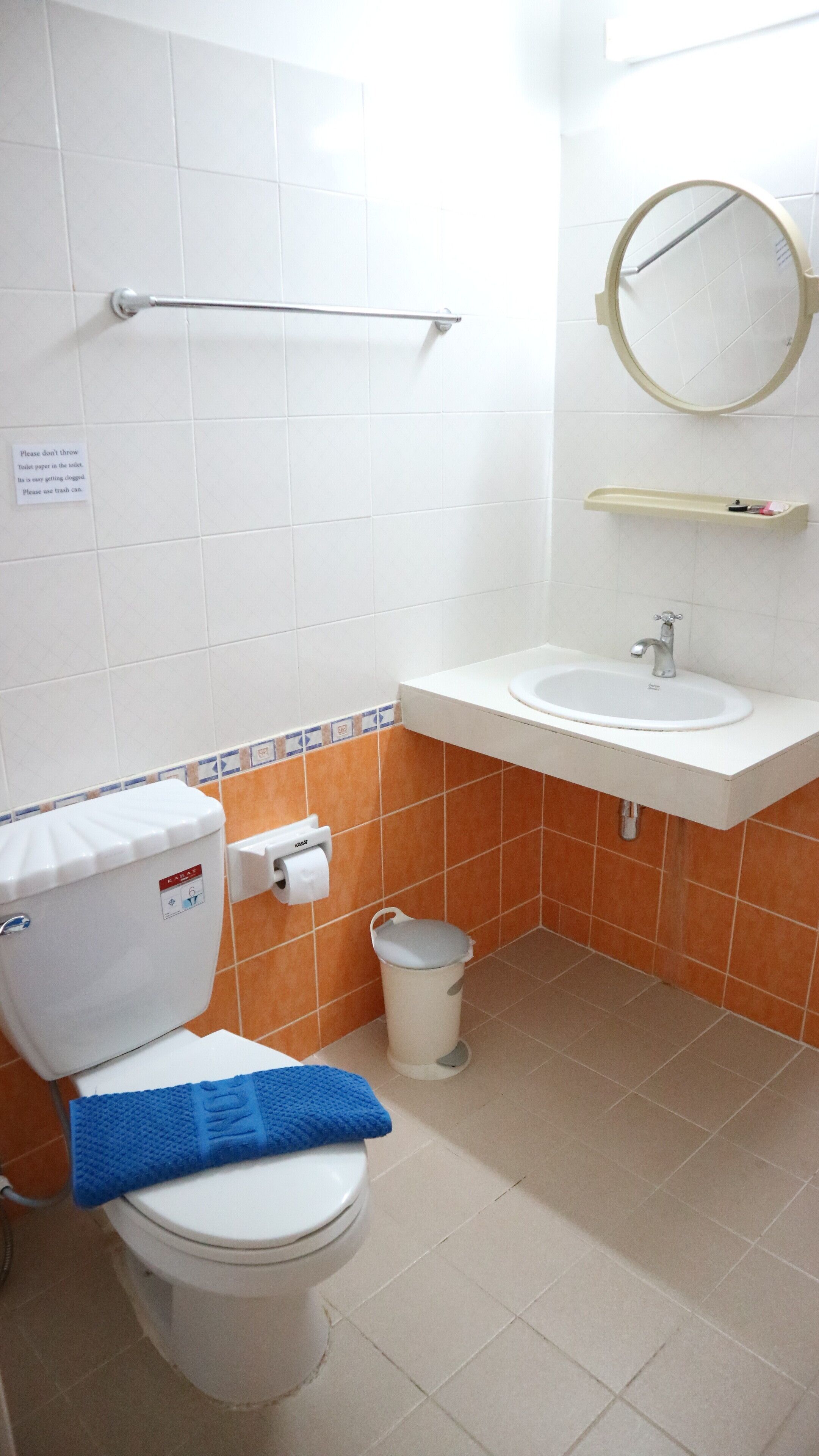 Un baño con inodoro, lavamanos y cubo de basura.