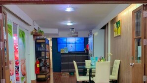 L’intérieur d’une maison d’hôtes comprenant un coin repas, une cuisine et un comptoir d’accueil.