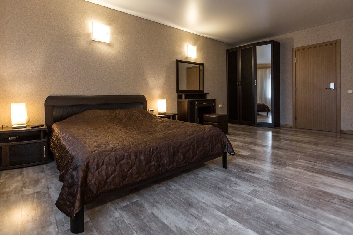 Un dormitorio con una cama grande, mesitas de noche, un aparador, un espejo y un armario.