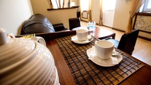 A dining table with two white cups and saucers, a large white pot, and a woven placemat. - Nachalnik Kamchatki (Petropavlovsk-Kamchatskiy)