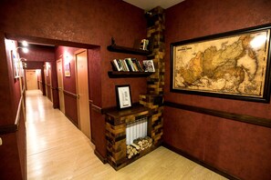 A hallway with a brick fireplace, wooden shelves with books, and a framed map on the wall. - Nachalnik Kamchatki (Petropavlovsk-Kamchatskiy)