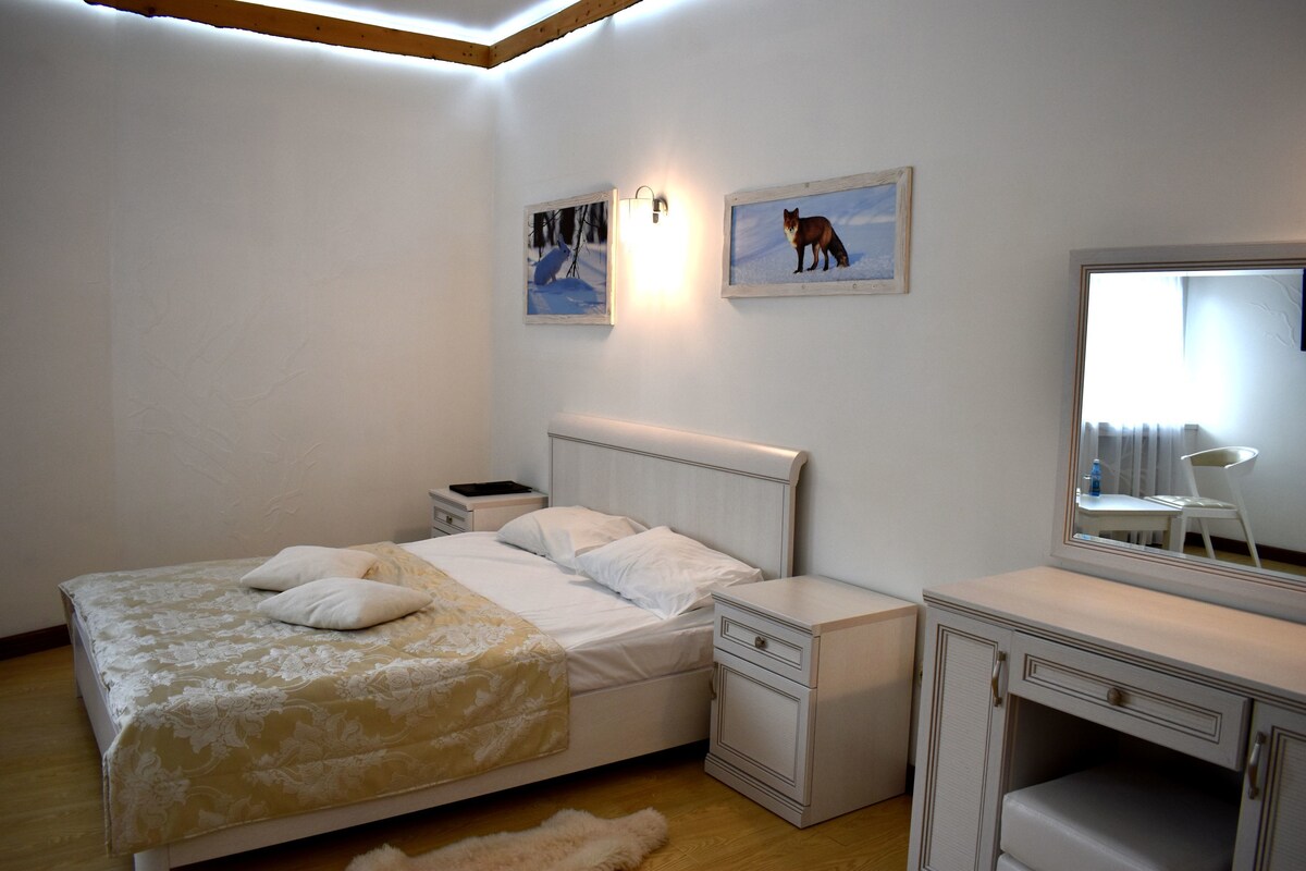 Un dormitorio con cama, mesitas de noche, cómoda y espejo.