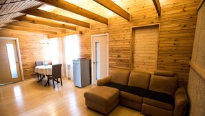 A wooden interior with a sofa, a table with chairs, and a refrigerator. - Nachalnik Kamchatki (Petropavlovsk-Kamchatskiy)