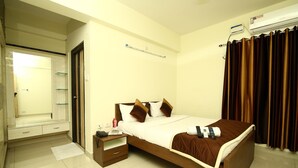 A hotel room with a bed, bedside table, and a mirror. - Fresh Living Prime Hi Tech (Hyderabad)