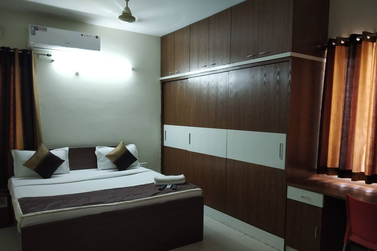 A hotel room with a bed, wardrobe, and a desk area.