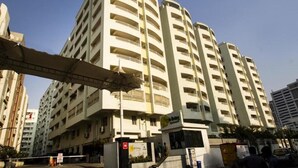 A multi-story hotel with a curved facade, balconies on each floor, and a central entrance. - Fresh Living Prime Hi Tech (Hyderabad)