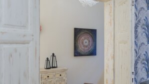 A room with a white wooden cabinet, a small wooden stool, and a wall-mounted artwork. - Pinkova Apartments (Prague)