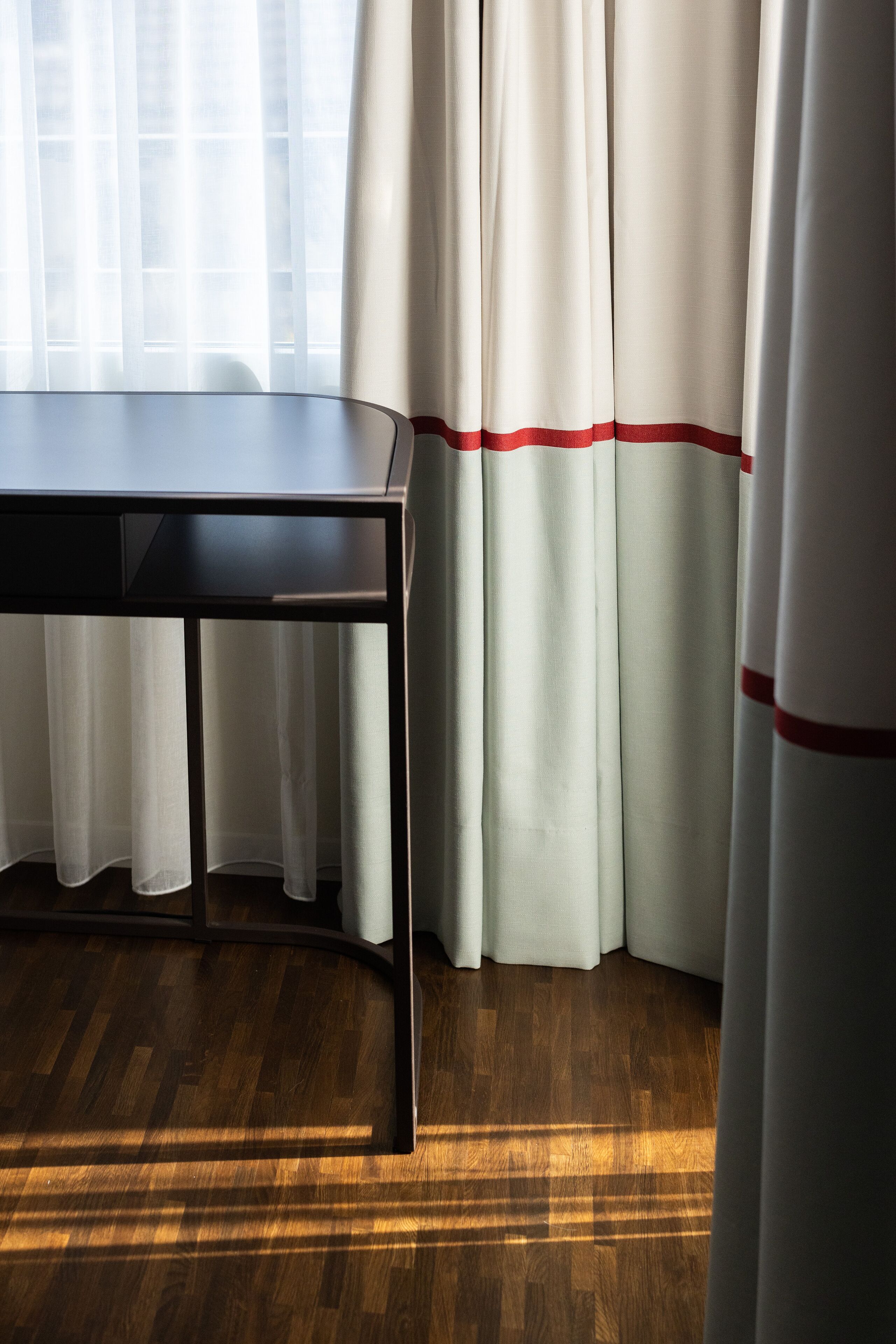 Une pièce avec un plancher en bois, une table et des rideaux à rayures rouges.
