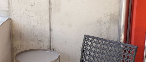 A chair with a white cushion and a metal frame, positioned next to a small round table with a metal frame.