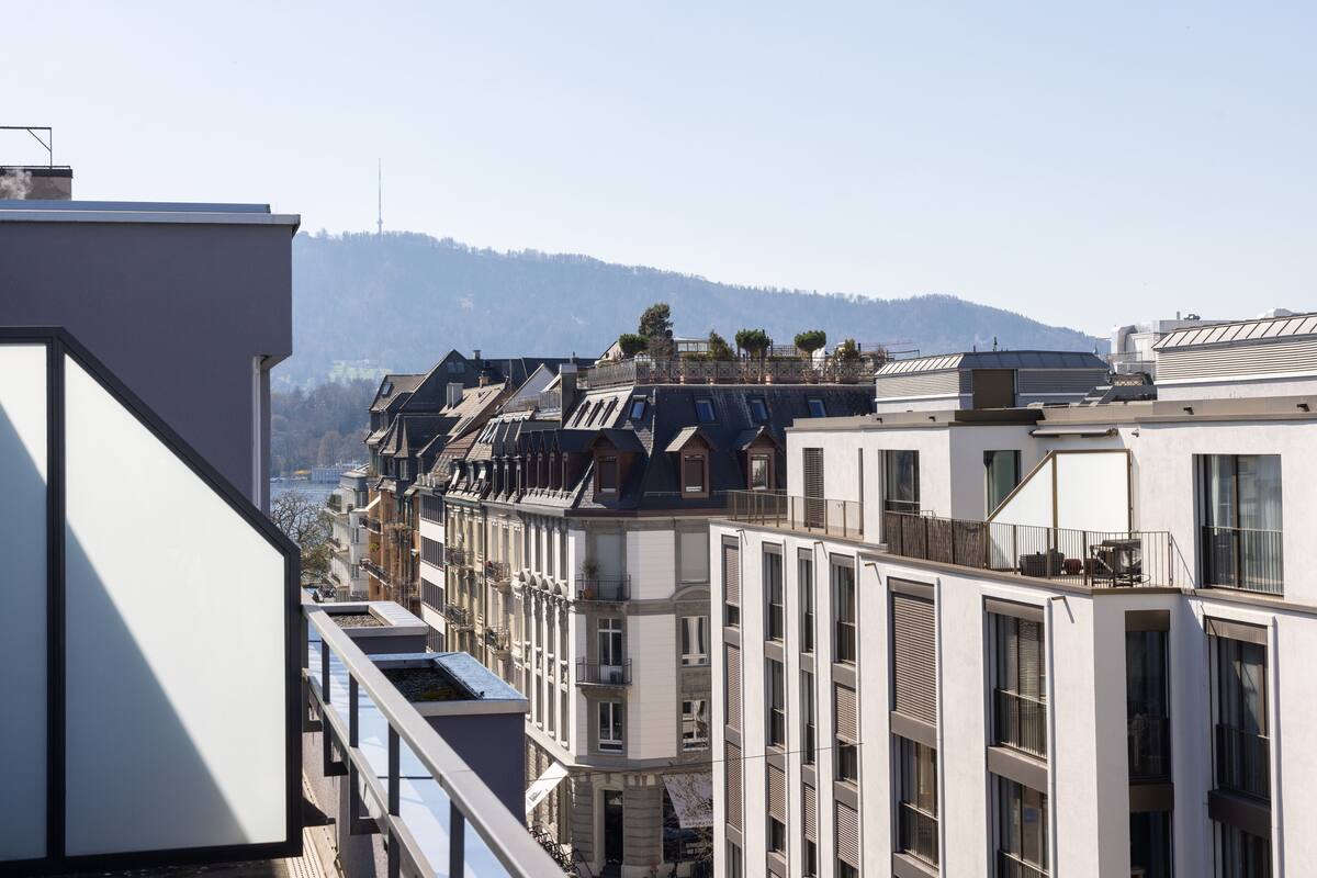 Une rangée de bâtiments modernes dotés de balcons, de grandes fenêtres et offrant une vue sur une montagne lointaine.
