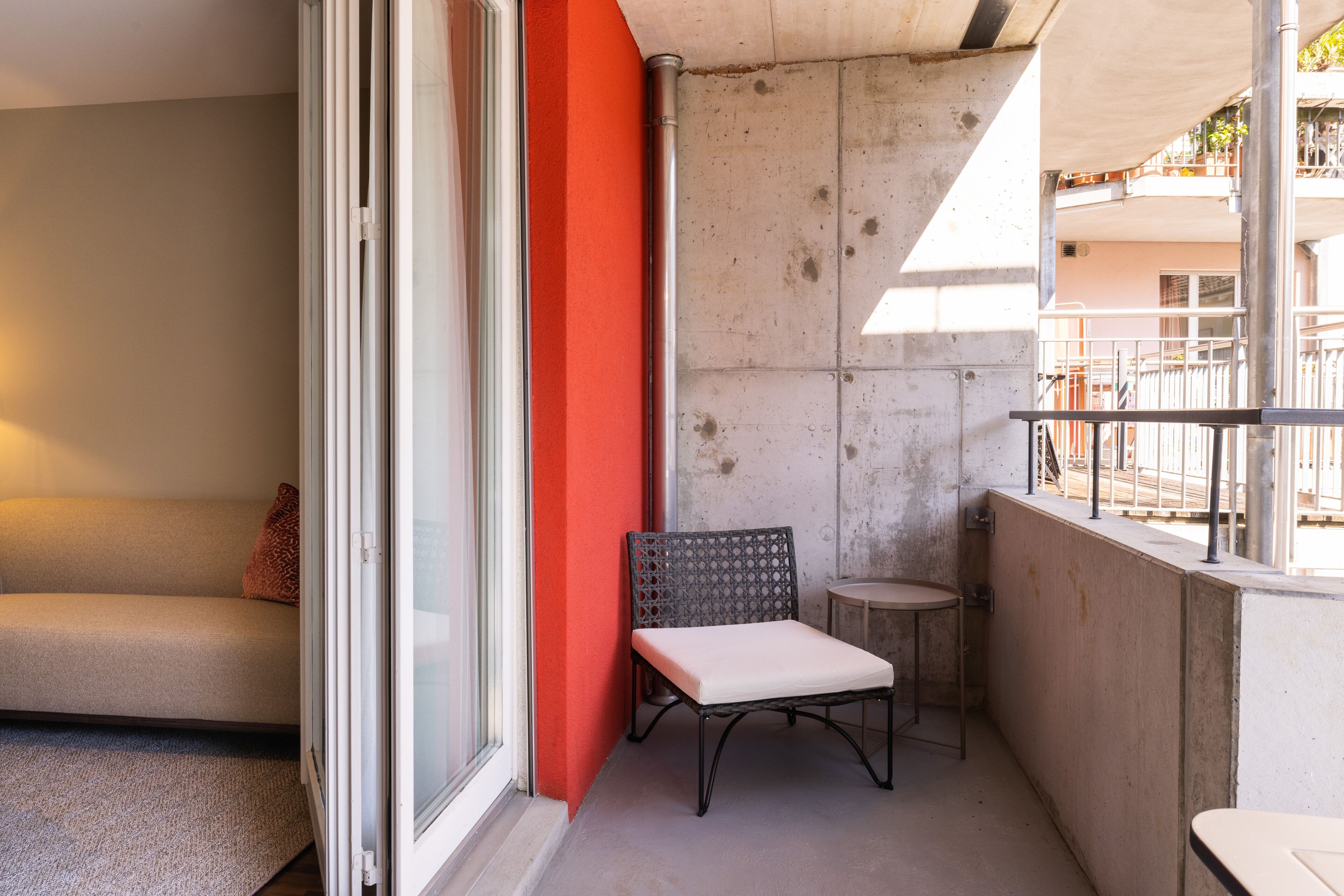 A balcony with a metal chair, a small round table, and a sofa.