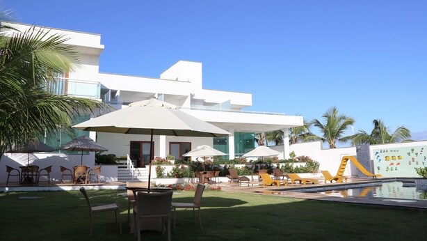 Un hotel moderno con zona de piscina, mobiliario exterior y área de juegos infantiles.