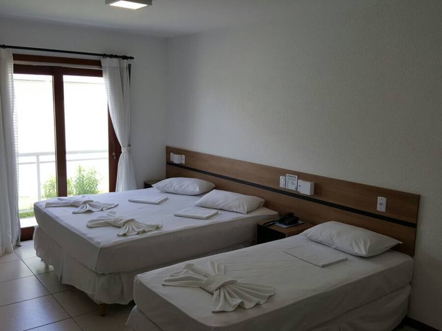 A hotel room with two beds, a television, and a window with curtains.