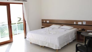 Habitación de hotel con cama, escritorio, silla y balcón.