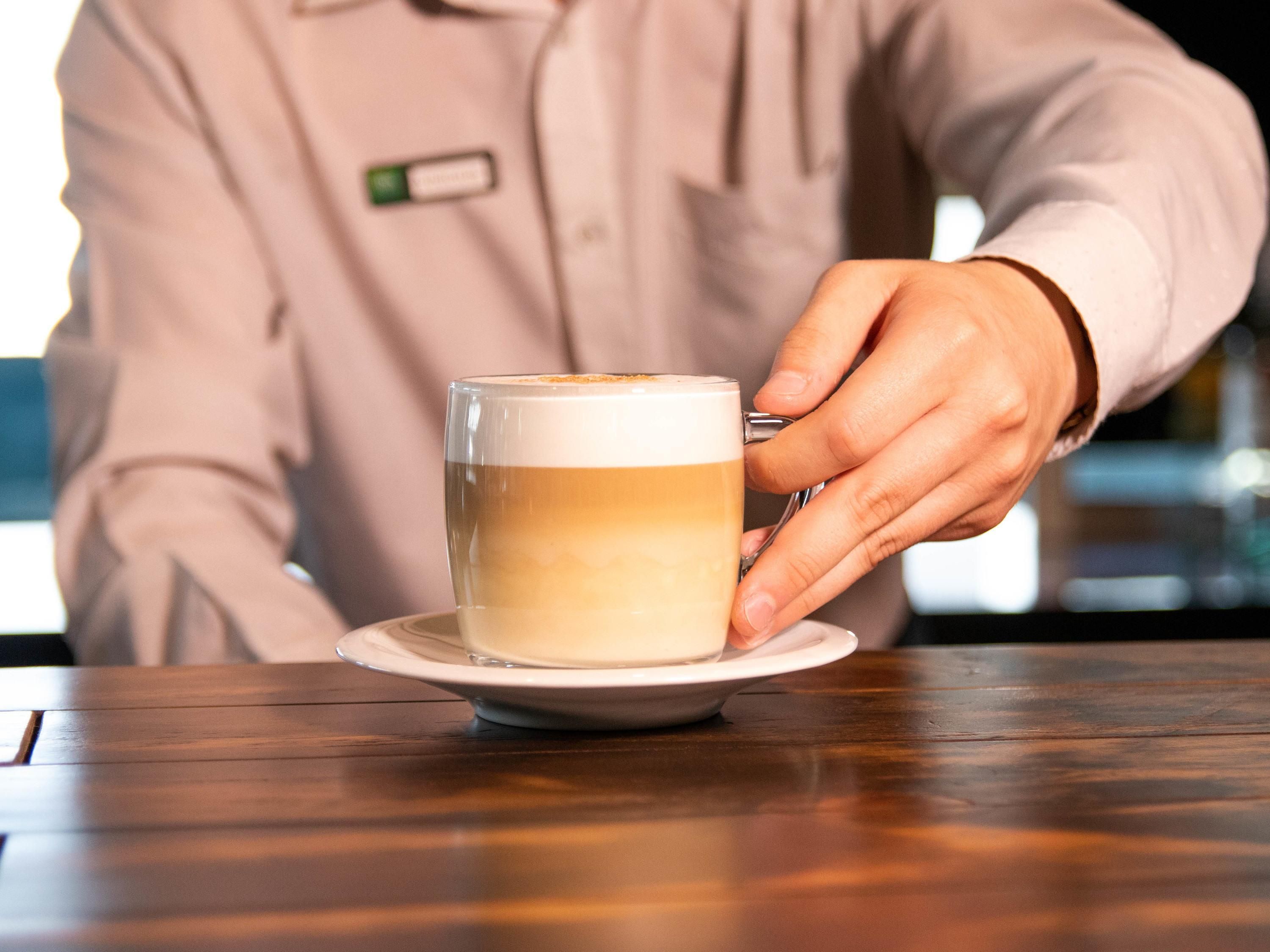 Une personne tenant une tasse de café sur une soucoupe.