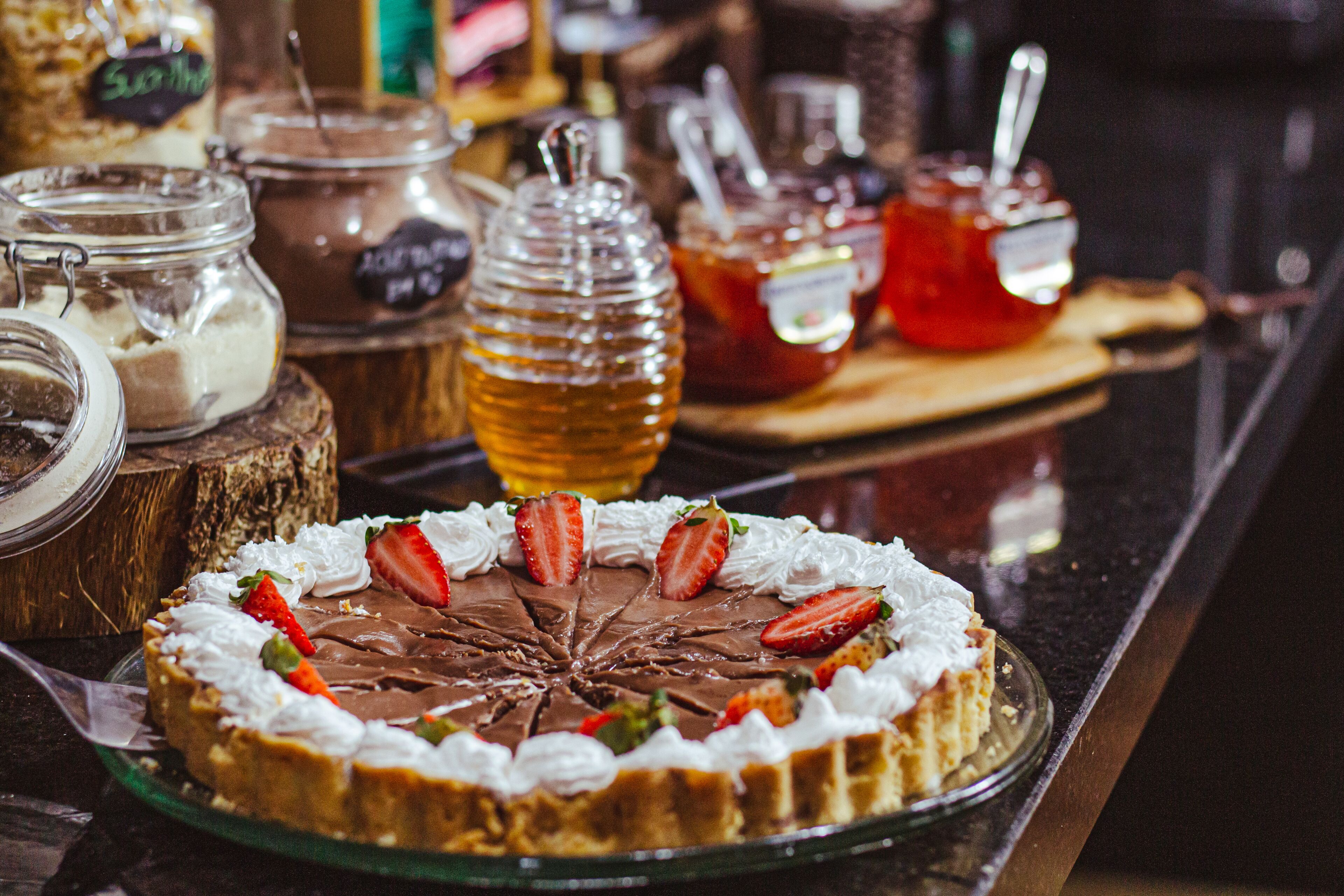 A dessert display with a chocolate tart, strawberries, and whipped cream.