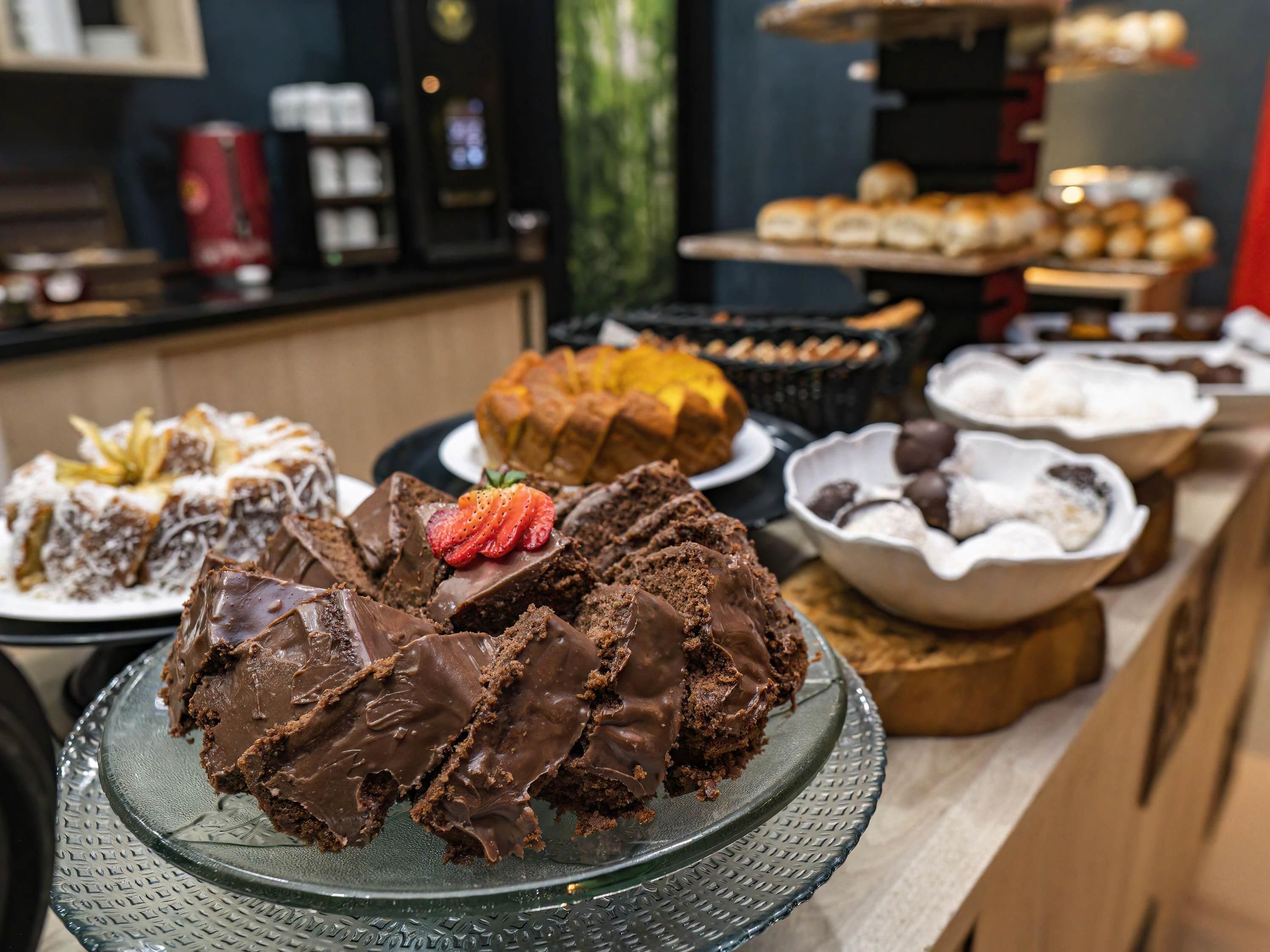 A variety of desserts on display, including a chocolate cake with a strawberry on top.