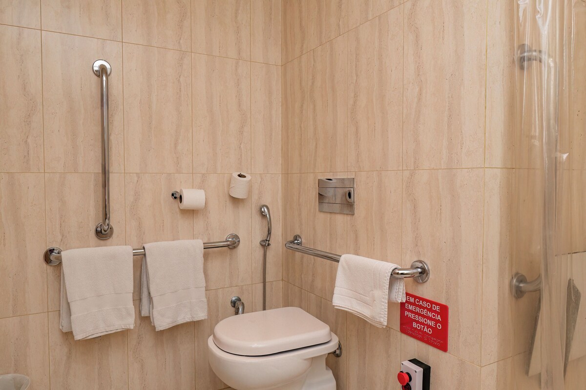 Een badkamer met toilet, handgrepen en een handrail.