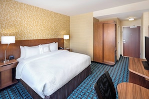 A hotel room with a large bed, bedside tables with lamps, a desk, and a wardrobe. - Fairfield Inn & Suites by Marriott North Bergen (North Bergen)