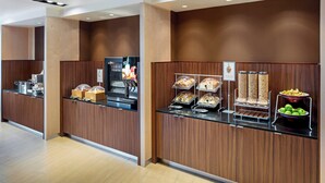 Zona de bufé con paneles de madera y una variedad de alimentos, como pasteles, sándwiches y frutas.