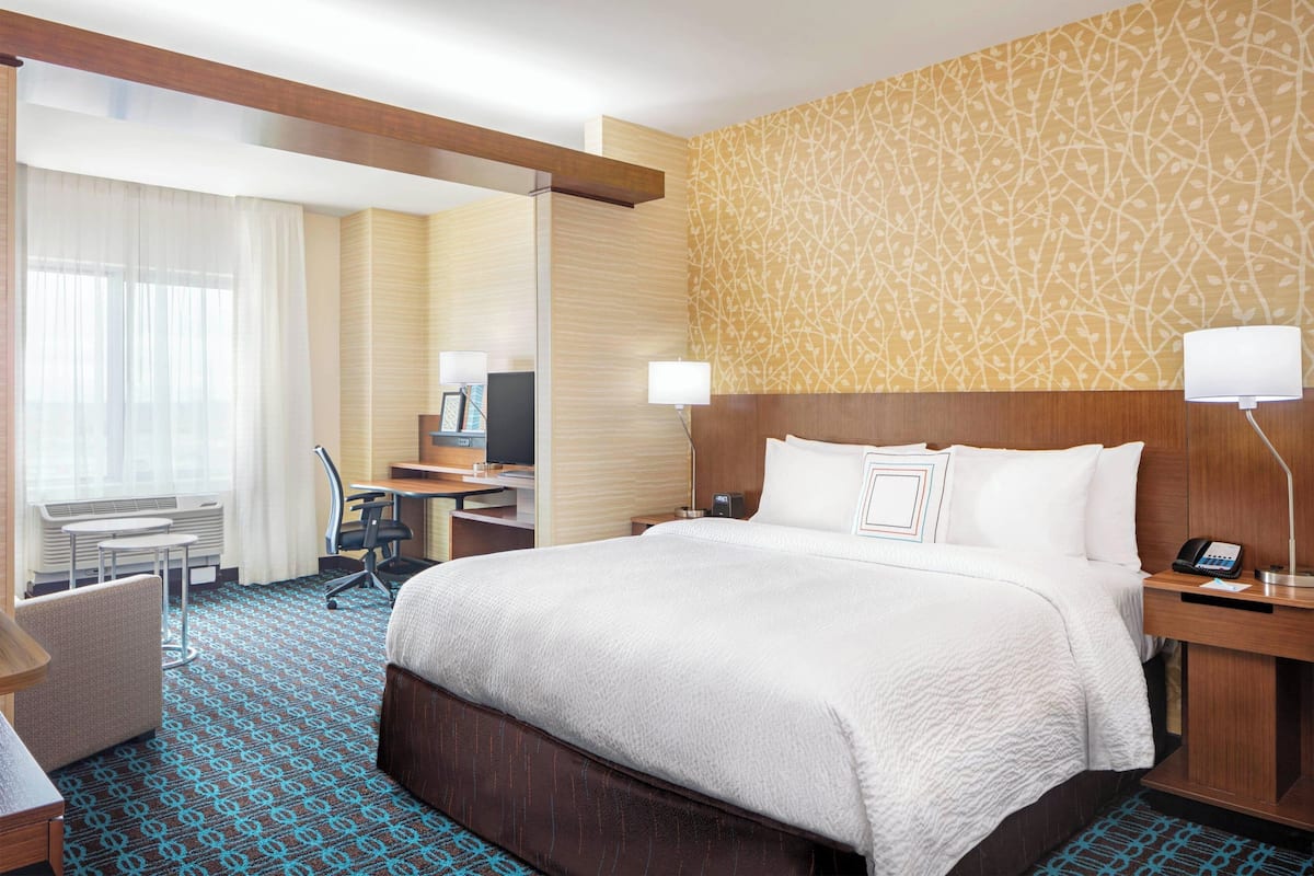 Une chambre d’hôtel avec un grand lit, un bureau, une chaise, une télévision et une lampe.