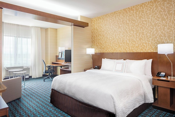 A hotel room with a large bed, a desk, a chair, a TV, and a lamp. - Fairfield Inn & Suites by Marriott North Bergen (North Bergen)