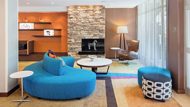 Un área de descanso moderna con chimenea de piedra, asientos azules y una pequeña mesa.