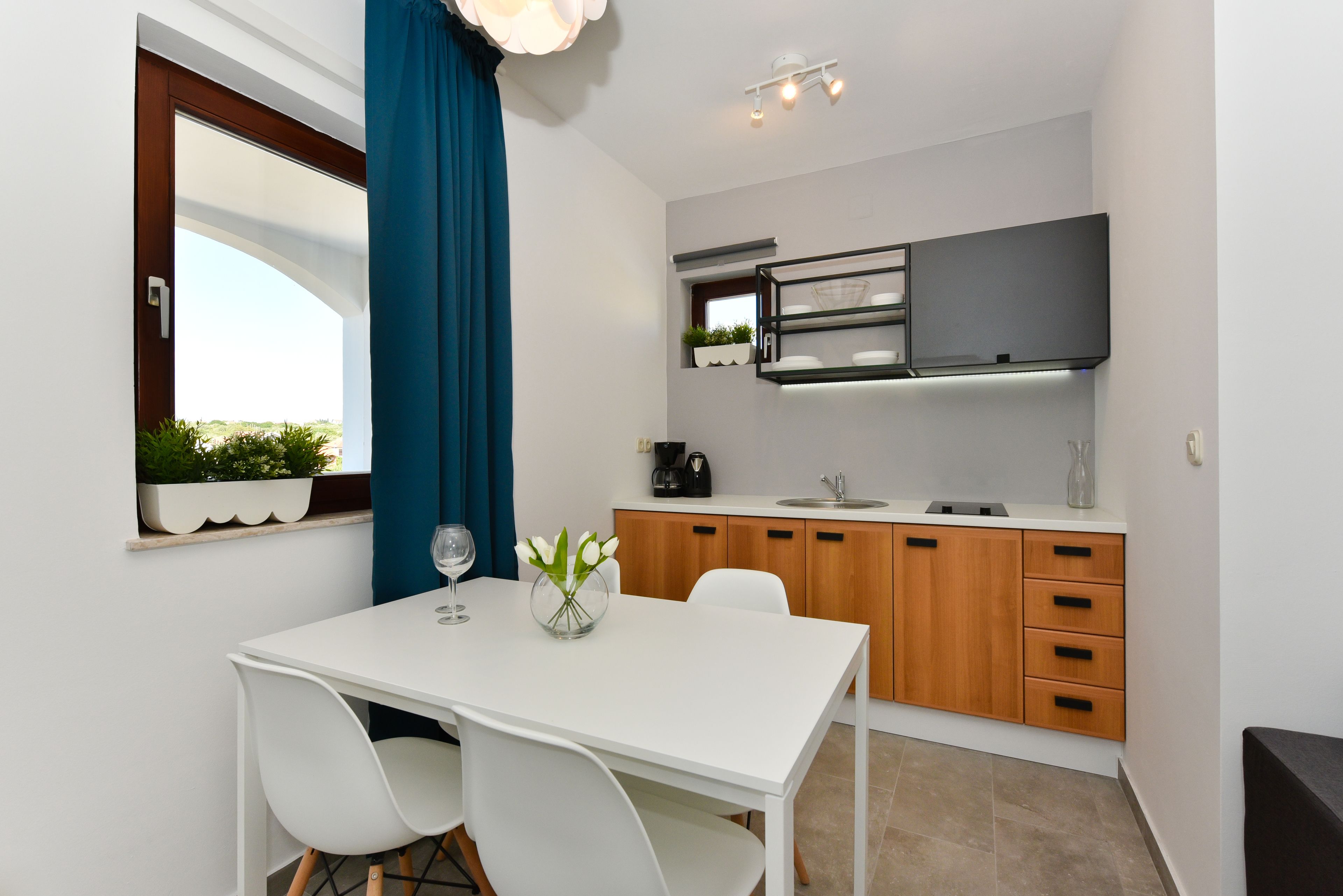 A compact kitchen with a white countertop, wooden cabinets, and a built-in oven.