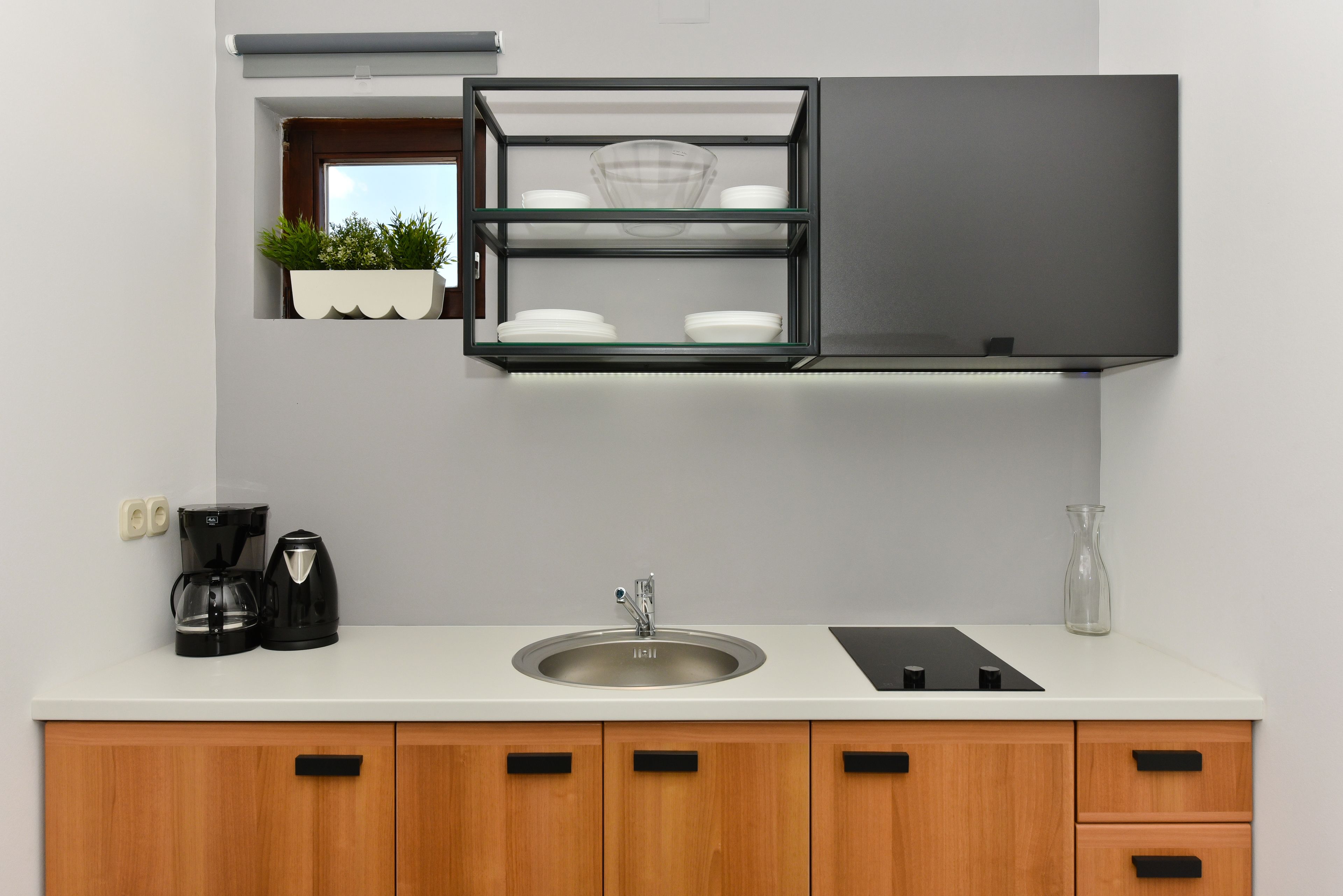 Una cocina moderna con un lavamanos integrado, una cafetera y un florero de vidrio sobre la encimera.
