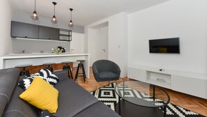A modern living room with a sofa, a coffee table, and a TV mounted on the wall. - Mediterraneo Garden Apartments (Zadar)