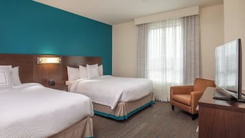 Een hotelkamer met twee bedden, een televisie en een bureau.