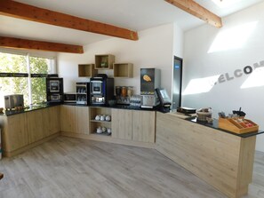 A modern kitchen with wooden cabinets, a coffee machine, and a digital scale. - Hôtel Restaurant L'Ermitage (Les Salles-sur-Verdon)