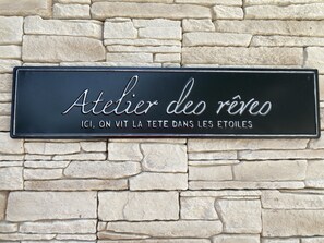 A sign with the text "Atelier des rêves" and "ICI, ON VIT LA TETE DANS LES ETOILES" on a stone wall background. - Hôtel Restaurant L'Ermitage (Les Salles-sur-Verdon)