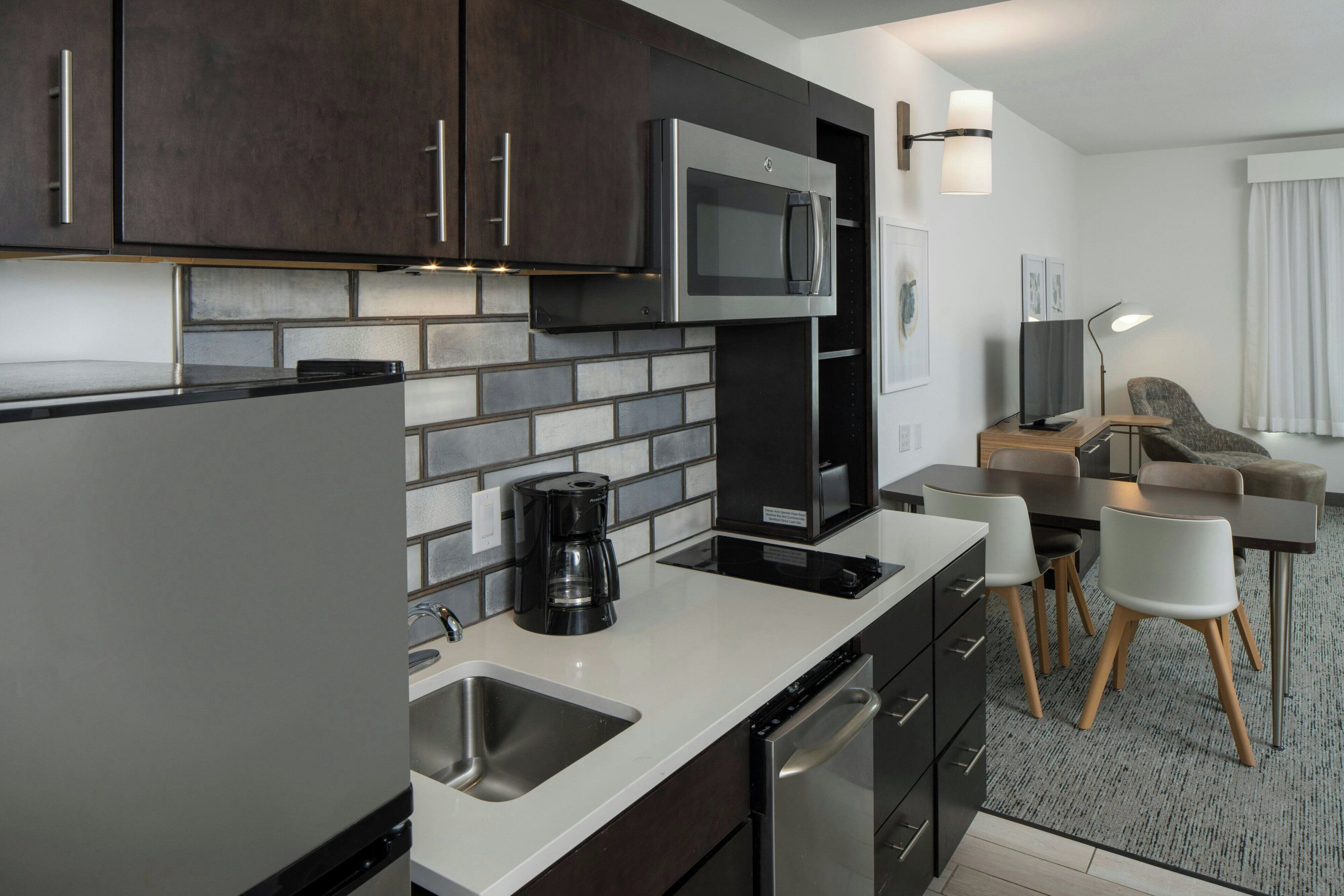 A modern kitchen with stainless steel appliances, a coffee maker, and a dining area with a table and chairs.
