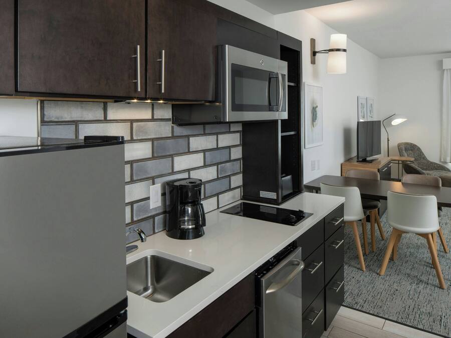 A modern kitchen with stainless steel appliances, a coffee maker, and a dining area with a table and chairs.