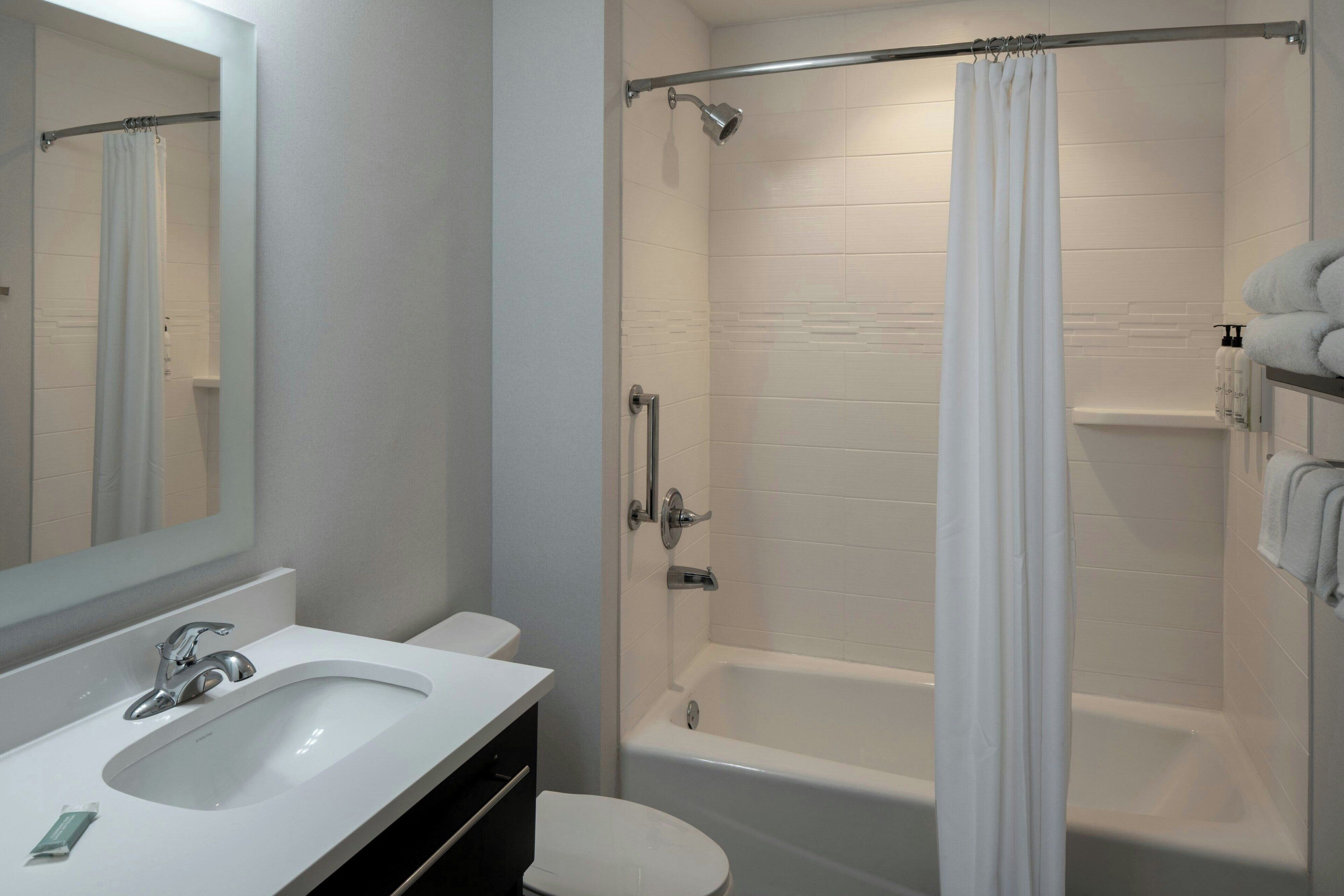 Une salle de bain moderne avec un lavabo, des toilettes et une baignoire, le tout de couleur blanche.