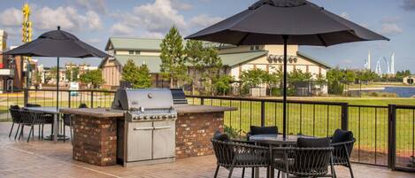 Une terrasse extérieure équipée d’un barbecue, de chaises et de parasols.