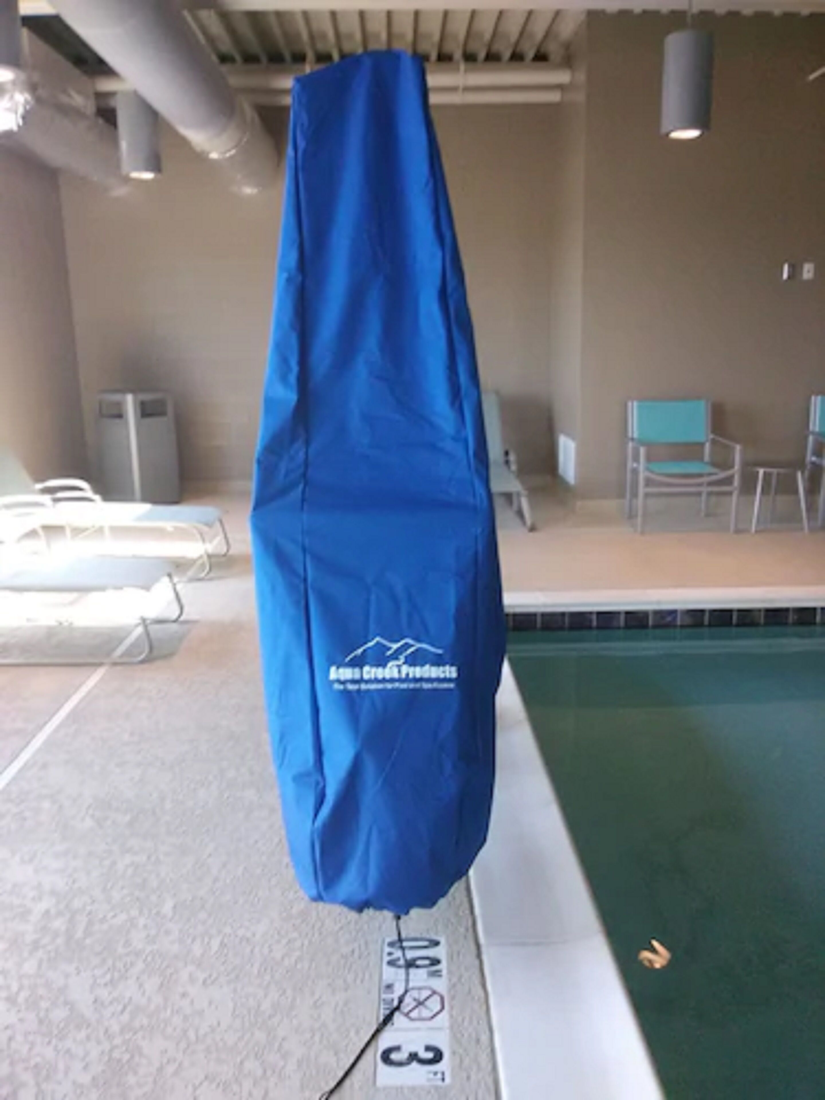 Une bâche bleue recouvre une partie de la piscine, et un panneau indique une profondeur de 3 pieds.