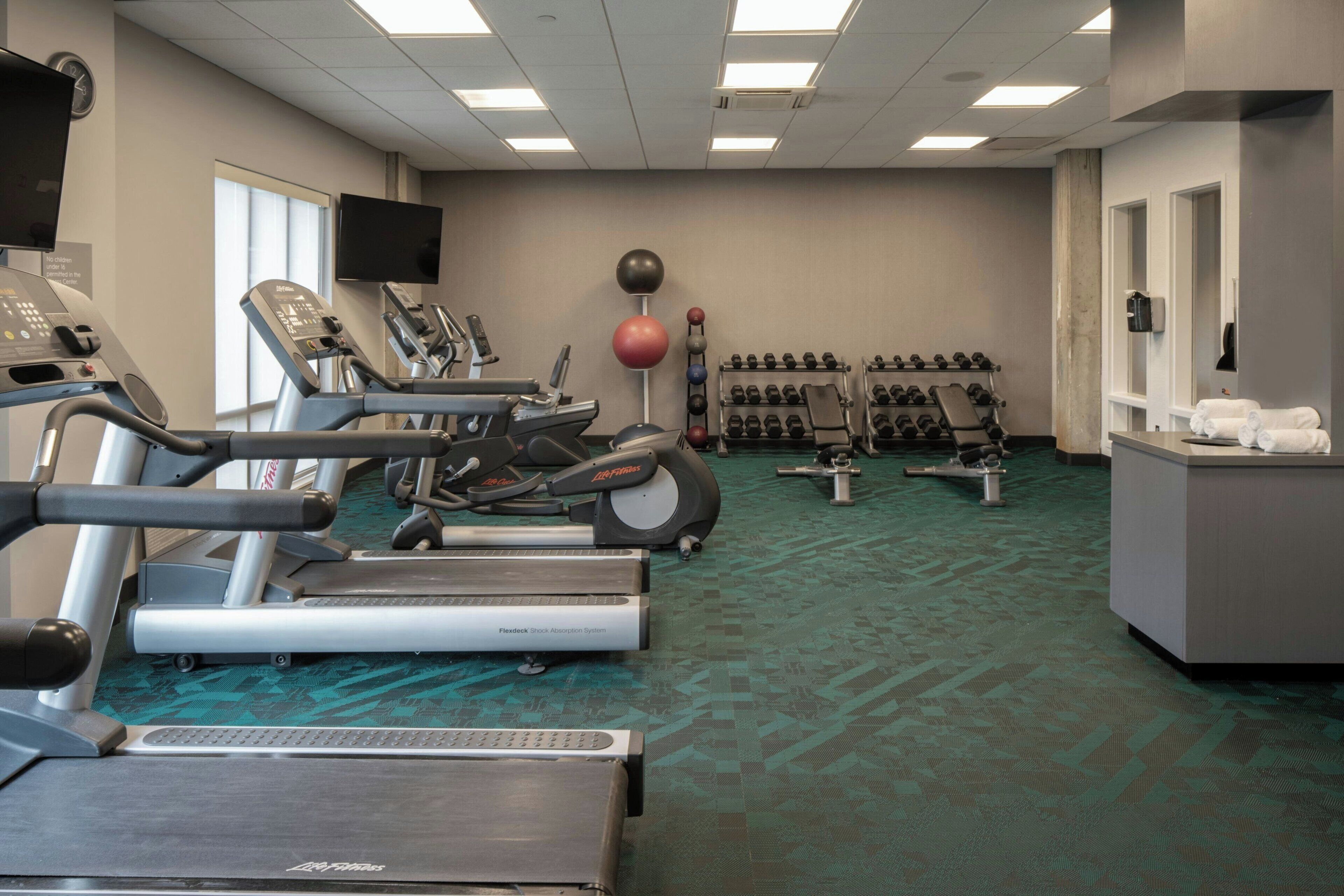 A gym with treadmills, elliptical machines, and free weights.