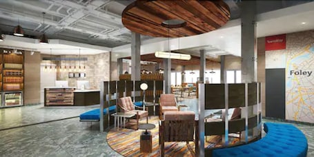 A modern hotel lobby with seating areas, a reception desk, and a map on the wall.