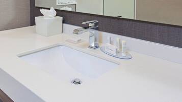 Une salle de bain moderne avec un lavabo blanc, un robinet argenté et un miroir au-dessus.